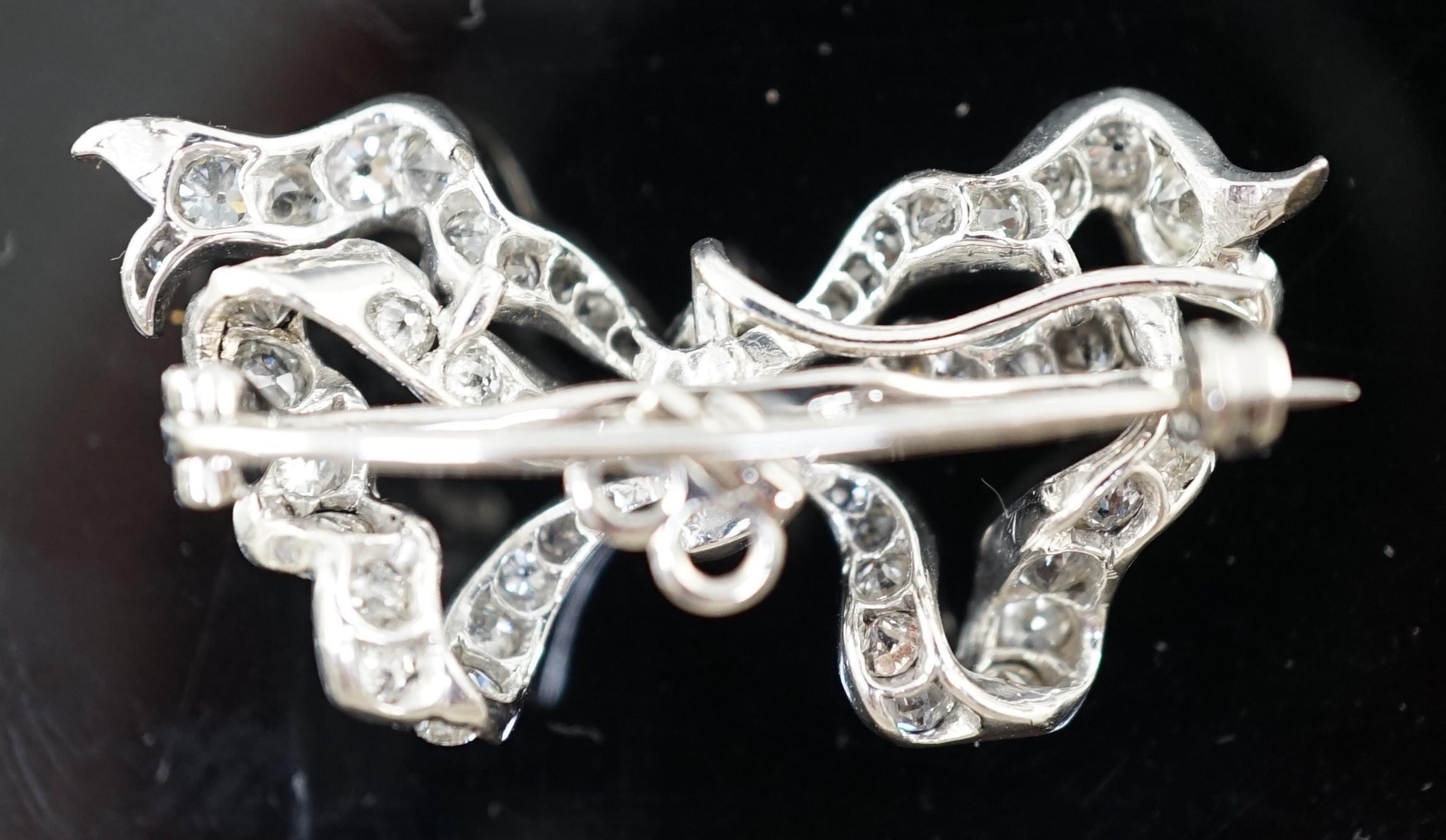 An early to mid 20th century platinum and diamond cluster set ribbon bow pendant brooch